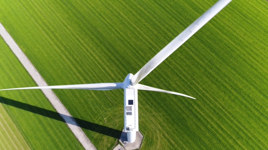 Aerial footage of wind turbine providing sustainable energy by spinning blades the power also known as renewable is collected from resources green field meadow in background 4k high resolution | Shutterstock HD Video #1042994104