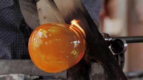 The process of shaping a crystal glass products.  Close-up shooting of the process of shaping a crystal glass products. Hot glowing crystal glass. Glassblowing.