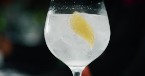 Close up of a professional bartender is mixing gin tonic with professional crystal ice cubes to customers at the bar or disco club.