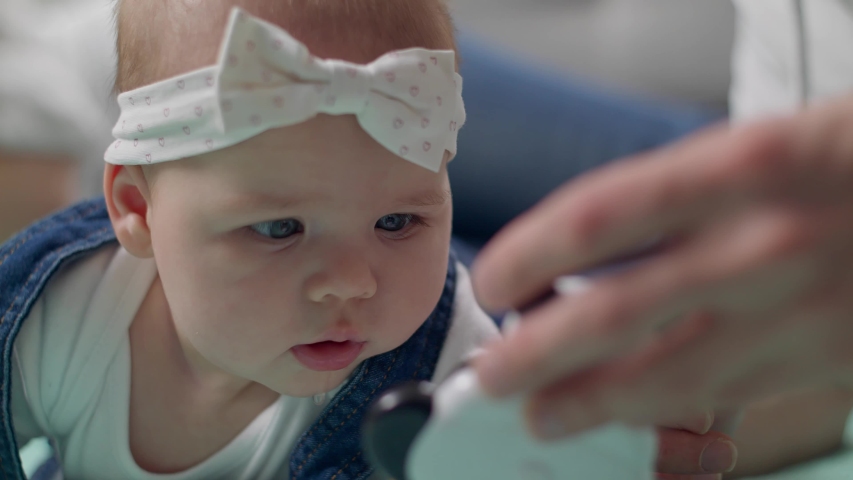 Little girl kid plays a rattle on the floor with parents