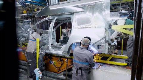 Workers welding a car carcass inside an automobile manufacturing plant
