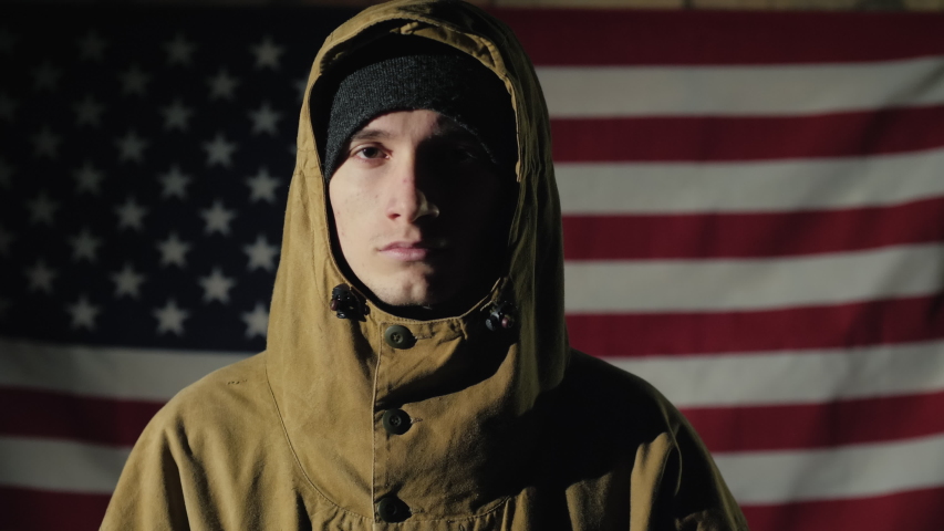 Portrait of a young male soldier on the background of the American flag