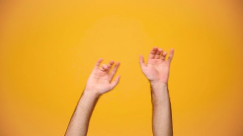 Man holds two hands depicting heavy metal rock sign, rock-n-roll horns up isolated on yellow background in studio. Copy space for advertisement. With place for text or image. Advertising area, mock up