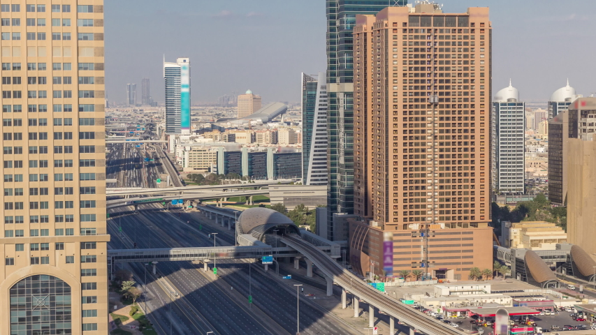 Skyline internet city with crossing Sheikh Zayed Road aerial timelapse before sunset. Skyscrapers with traffic on a highway and metro line in Dubai
