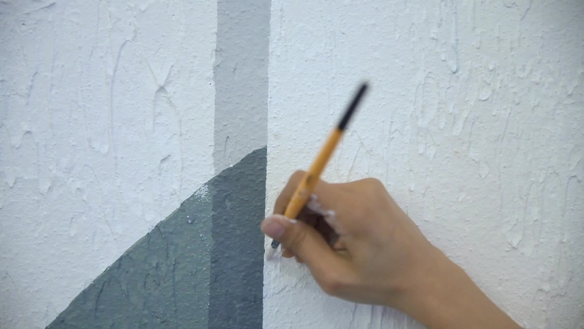 Female hand paiting the Wall with brush white paint
