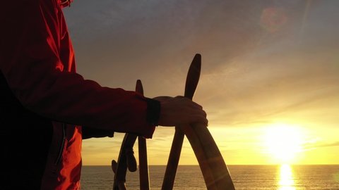 Man holding ship rudder in sunset light.