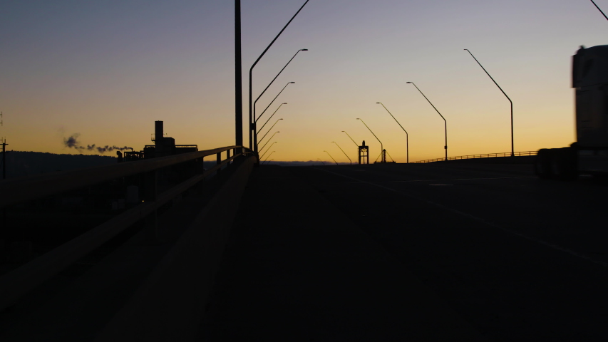 Silhouetted car & truck traffic crossing bridge in Industrial Long Beach CA