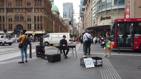 Sydney, NSW / Australia - Dec 13 2019: street performance busking entertaining pedestrian at Town Hall QVB. young male pianist play electric keyboard for people to people donate money