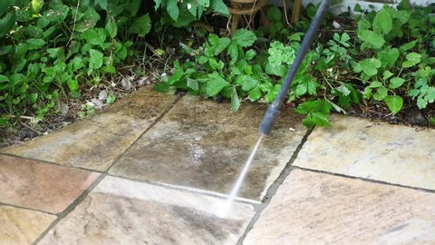 Cleaning the tiles on the patio floor with a high pressure cleaner