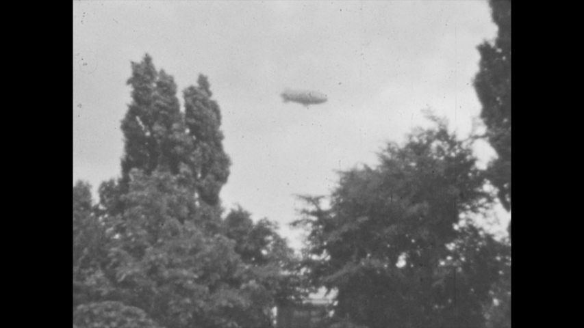 1940s: UNITED STATES: American flags outside stone building and arches. Cars in road. Stone wall and steps.