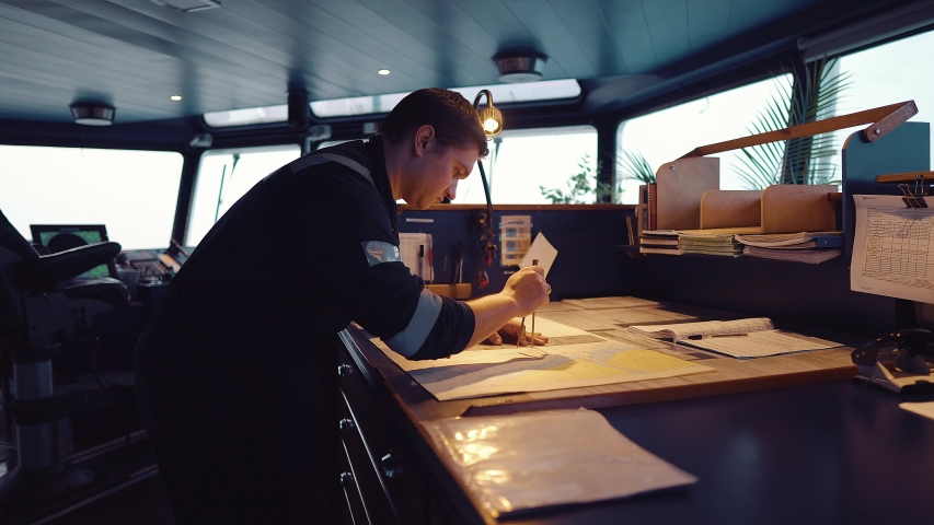 Marine navigational officer during navigational watch on Bridge . He does chart correction of nautical maps and publications. Work at sea Royalty-Free Stock Footage #1043046097