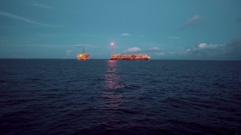 FPSO tanker vessel near Oil Rig platform. Offshore oil and gas industry. Flare is burning with smoke. View from supply vessel.