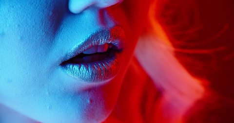 Close up of lips with glowing lipstick blowing a sensual kiss in neon light - nightlife concept 4k footage