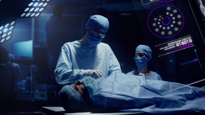 Professional Medical Surgeons perform a Delicate Operation while observing Anatomical Data on Transparent Screens. Modern medical equipment. Royalty-Free Stock Footage #1043051536