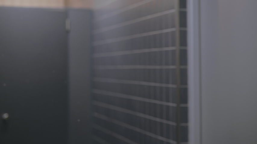 Serious mature businessman in suit and white shirt prepares himself to business meeting and comes to the mirror fixing cleaning clothes and his grey hair. Man tunes in before negotiations