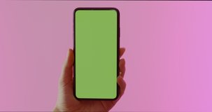 GREEN SCREEN CHROMA KEY CU Caucasian female using modern smart phone, vertical orientation, colorful neon background. 4K UHD RAW Graded footage