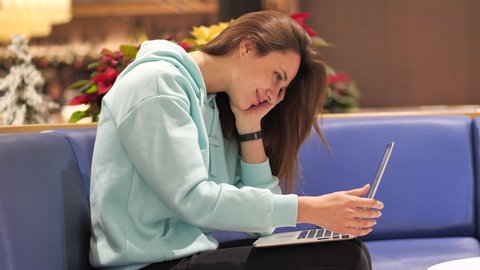 a young woman in a sweatshirt develops an application, she smiles clicks on a laptop and tests it 4k