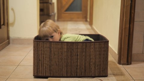 Little kid playing home hiding into a box