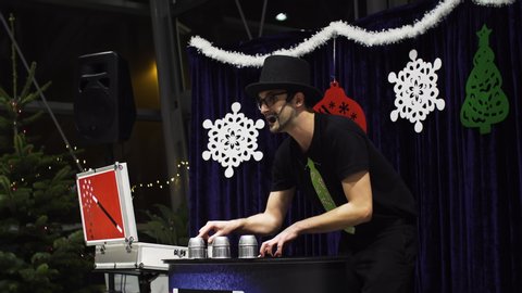 Ljubljana / Slovenia - December 2019:
Attractive magician in a black hat talks and perform his tricks to the audience. Scene. Show. 