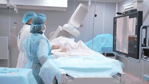 Coronal bypass surgery in the operating room. Doctors perform surgery, coronary artery bypass grafting. The doctor looks at the monitor during surgery. The work of medical staff in the operating room.