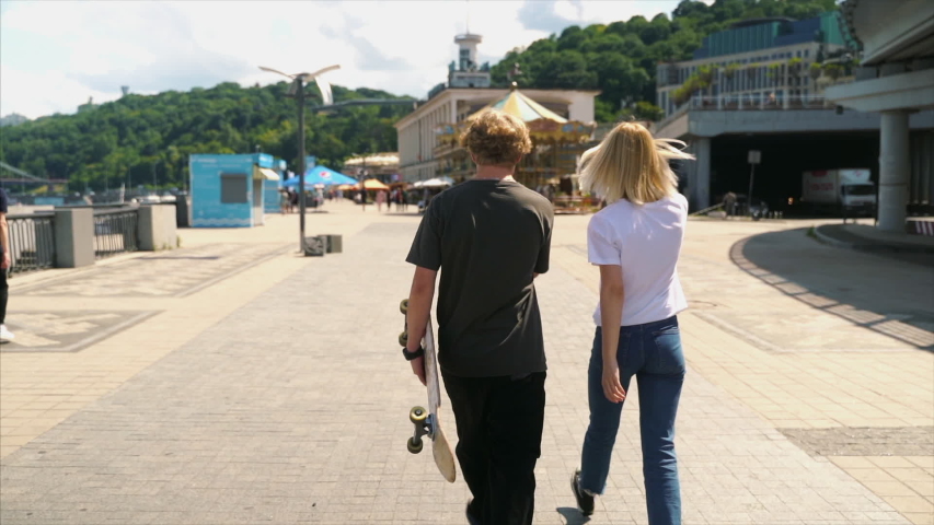 A guy and a girl walk along the street together.