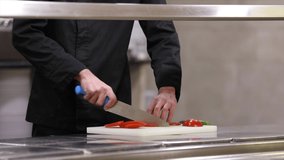 Chef cuts vegetables, tomatoes and cucumbers