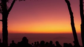 Time lapse,Crowd of silhouette people standing together and looking at the red sun is rising from the horizon on the Mountain