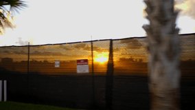 Motion video sunset through a construction site fence