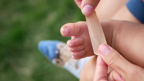 Adhesive plaster and childrens wound. Mom with Adhesive Bandage closes the wound to a small child. Matri care for the child when he is injured. Help baby.