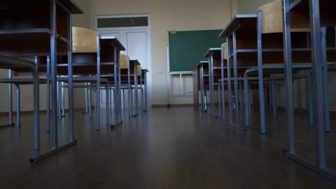 empty classroom during a quarantine, shut down because of virus, break or vacation at school, university, institute, slow motion towards green blackboard, between two rows of desks