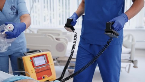 VINNITSA, UKRAINE - September 2019:  Reanimation of patient with defibrillator. Doctor using external defibrillator during resuscitation in hospital