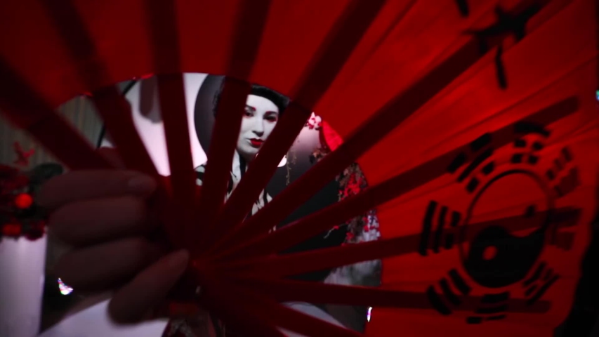 Japanese geisha in traditional makeup and clothes with a fan in his hands