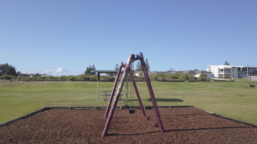 Swings in empty Australian playground in the morning