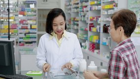 asian pharmacist supply medicine to female patients in pharmacy store Thailand 