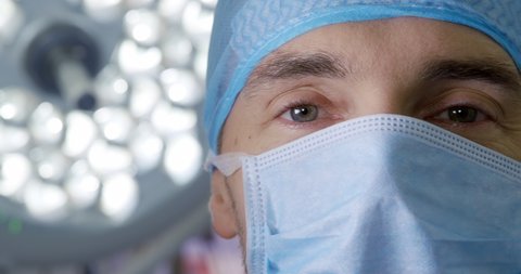Caucasian male healthcare professional in a hospital operating theatre wearing a surgical cap and mask. Healthcare workers in the Coronavirus Covid19 pandemic