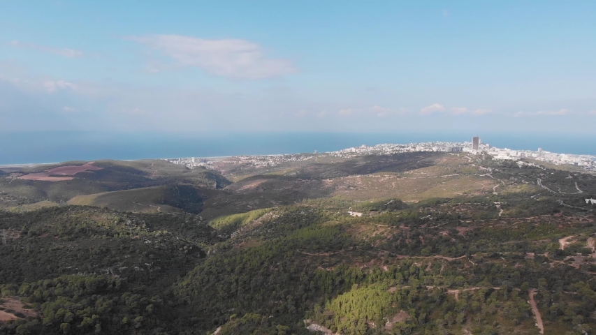 The slopes of Mount Carmel are not foreground. Haifa city and Haifa Bay in the background. Videography from a drone.