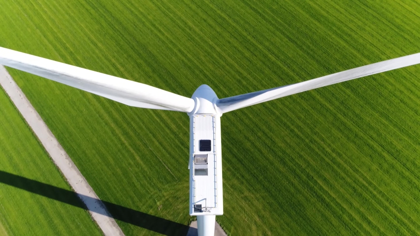 Aerial close up footage of wind turbine providing sustainable energy by spinning blades the power also known as renewable is collected from resources green field meadow in background 4k quality Royalty-Free Stock Footage #1043129581