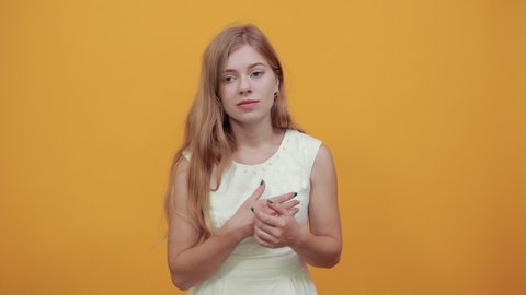 Charming caucasian blonde young woman keeping hands on neck, choking herself over isolated orange background wearing white shirt. Lifestyle concept