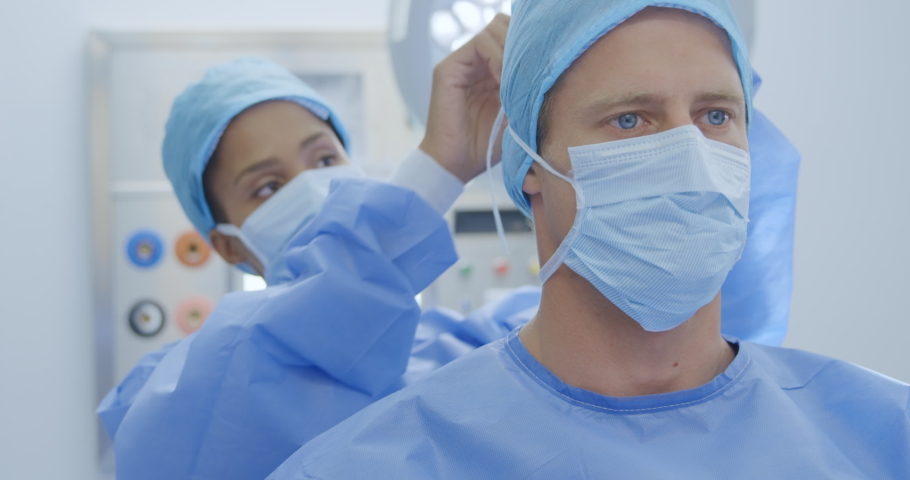 Front view close up of Caucasian male and female healthcare worker in a hospital, both wearing scrubs and caps. Healthcare workers in the Coronavirus Covid19 pandemic
