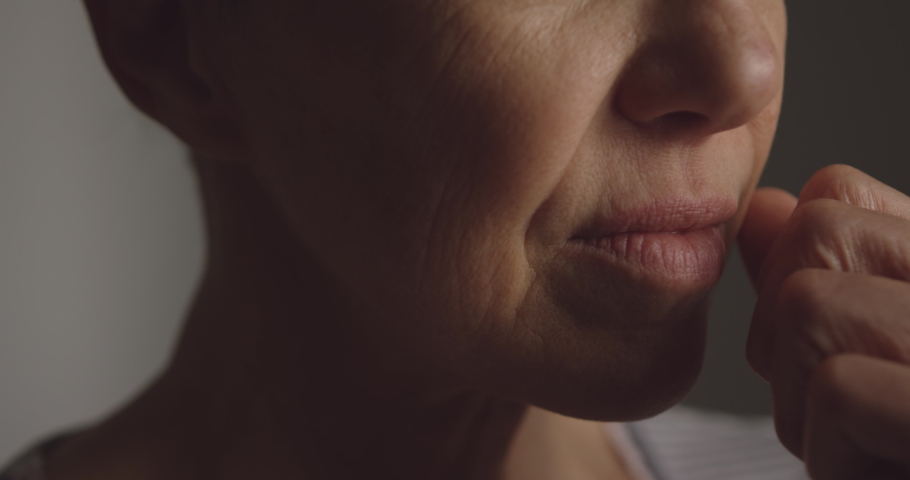 Head shot of a senior Caucasian woman with short grey hair at home, looking away in though, with her hand to her mouth, thinking, slow motion, Social distancing and self isolation in quarantine Royalty-Free Stock Footage #1043147920