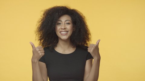 Girl approves, thinks choice is perfect. Attractive african-american woman in black t-shirt with afro haircut, nod in agreement, show thumbs-up, like accept and recommend product, wink happy