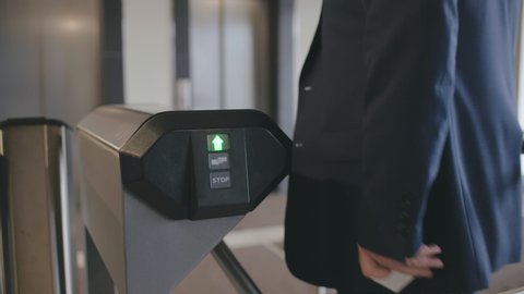 Businessman pass the electronic turnstile with plastic card entering modern office business center. Man in formal clothes use card to access control