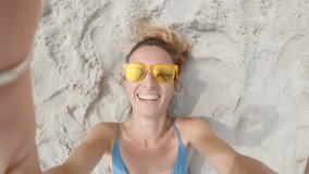 Woman taking cool selfies on the beach lying down on sand 