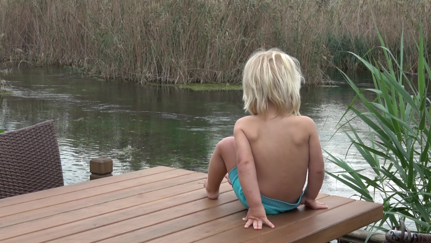 Akyaka, Mugla, Turkey - 9th of November 2019: 4K Blonde toddle on table turns back and looks in camera
