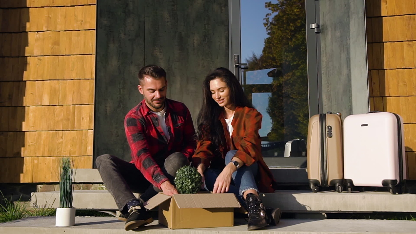 Front view of happy satisfied trendy couple which sitting on the new house