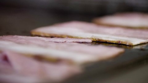 Close up of cooking crispy bacon on a Griddle or Skillet