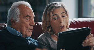 Close up of happy mature senior couple Having video call with a tablet in living room at home. Elderly Man and Woman Talking to Their Family and Friends Using Internet, Staying Connected