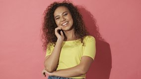 Cheerful pretty curly woman laughing and looking at the camera over pink background