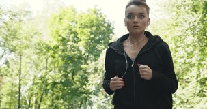 Young Adorable Woman Training in the Morning, Running while Listening to Music. Looking Pretty and Gorgeous. Beautiul Woman using her earphones, Motivating video shot.
