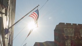 Detail of city urban American scenery, waving USA flag and flashing sun behind, real time video 
